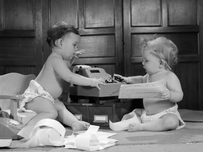 1960s-two-babies-wearing-diapers-in-business-office-with-adding-machine-playing-accountant