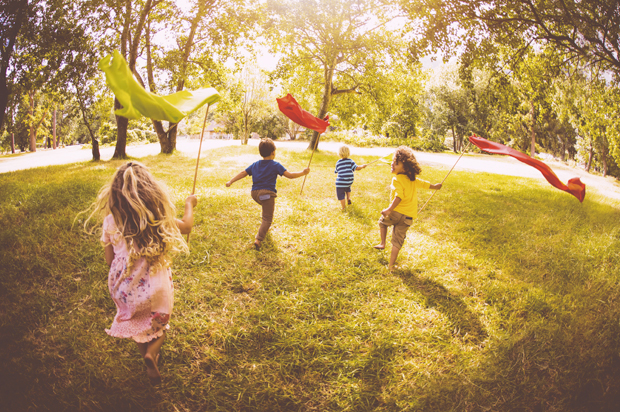 Children playing and running in a park with colourful banners