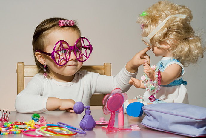 Little adorable girl playing with doll and toy sunglasses