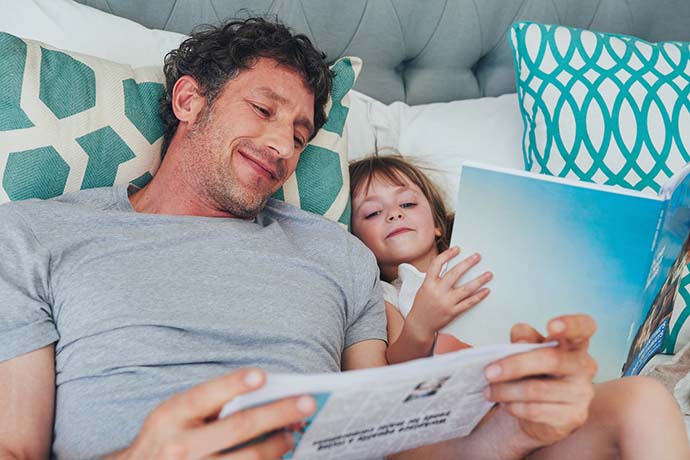 Dad and daughter bonding while reading in bed together